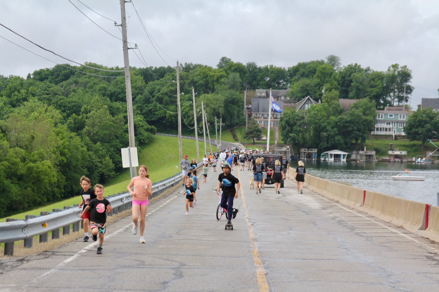 Residents running and skating across the Lake Lotawana dam